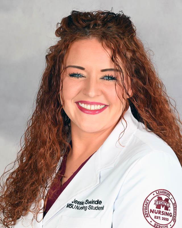 Mississippi State University Nursing student Jessica Swindle, with long hair wearing a white nursing lab coat.