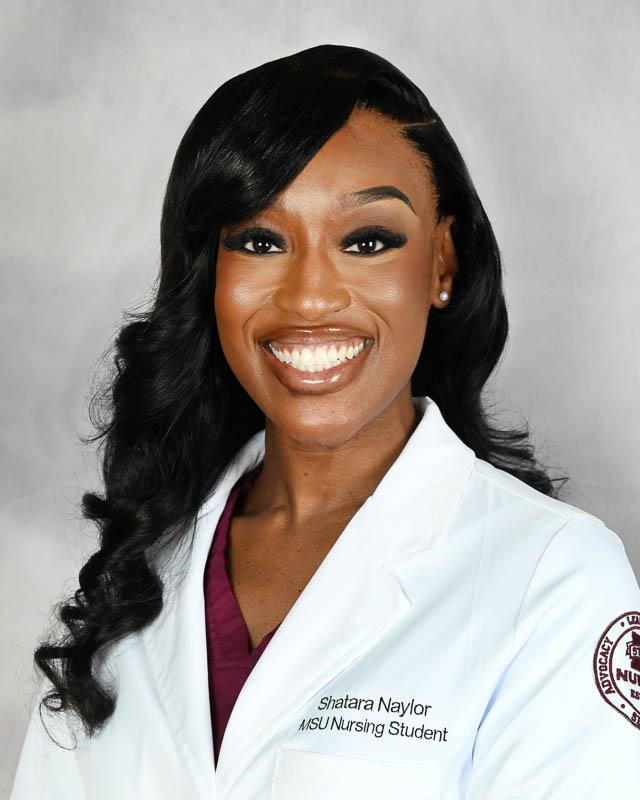 Portrait of Mississippi State University Nursing student Shatara Naylor with long hair wearing a white nursing lab coat.