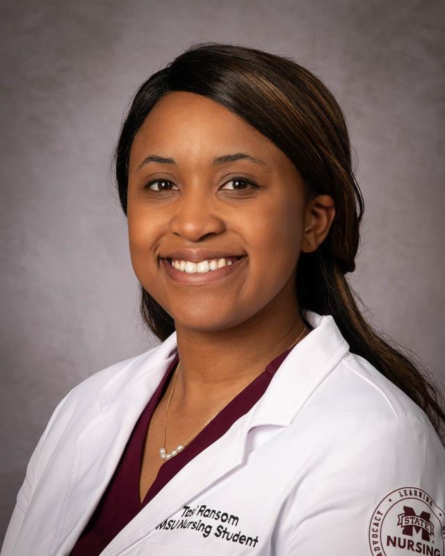 Portrait of Mississippi State University Nursing student Tasi Ransom with long hair wearing a white nursing lab coat.